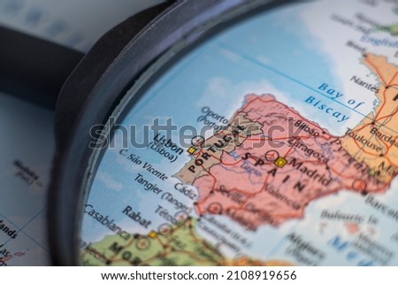Portugal on a world map through magnifying glass. Portugal travel destination planning pinned Royalty-Free Stock Photo #2108919656