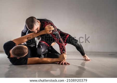 Brazilian jiu jistu bjj no-gi grappling training two male athletes drilling technique or sparring at gym academy guard position Royalty-Free Stock Photo #2108920379