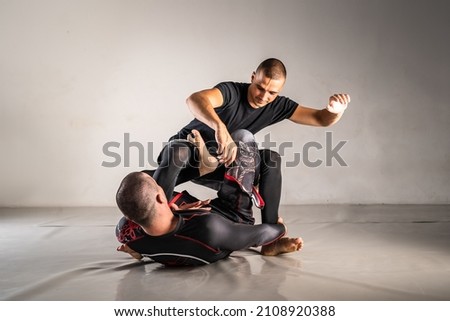 Brazilian jiu jistu bjj no-gi grappling training two male athletes drilling technique or sparring at gym academy sweep from guard position Royalty-Free Stock Photo #2108920388