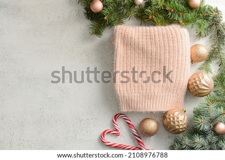 Composition with Christmas clothes, fir branches and decorations on light background
