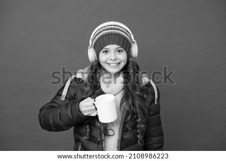Keep calm and drink hot milk. Happy girl hold milk mug red background. Little child enjoy music and milk tea. Modern life. Winter or autumn holidays. All you need is milk and music
