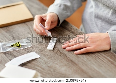 medicine, self testing and pandemic concept - close up of woman making coronavirus test and dropping reagent to cartridge at home Royalty-Free Stock Photo #2108987849