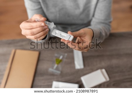 medicine, quarantine and pandemic concept - close up of woman making self testing coronavirus test at home