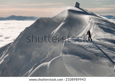Great view of beautiful mountain slope covered by fresh powder snow and photographer with camera on tripod standing on it