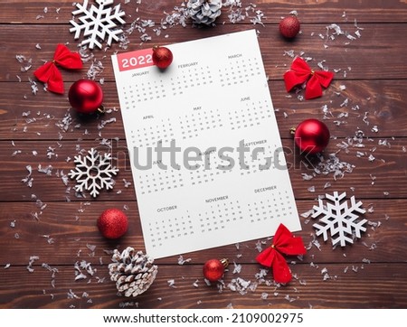 Paper calendar for year 2022 and Christmas decor on wooden background