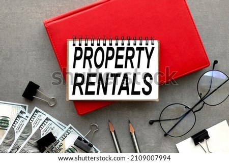 PROPERTY RENTALS text in open notepad on red notepad on gray background