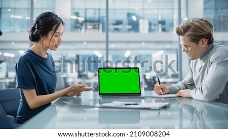 Multiethnic Diverse Office Conference Room Meeting: Team of Two Creative Entrepreneurs Talk, Discuss Growth Strategy, Use Laptop with Green Screen Mock Up Display. Royalty-Free Stock Photo #2109008204