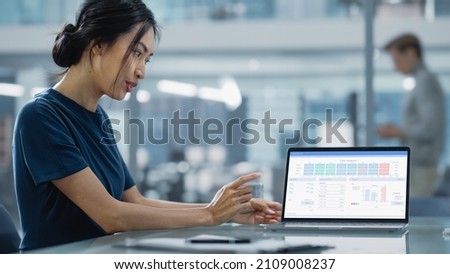 Multiethnic Office Meeting Room: Creative Asian Entrepreneur Female Use Laptop and Pointing on Screen with Financial Plan, Charts, Data.