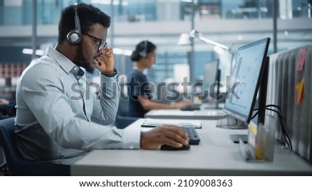 Professional Investment Traders Talking into Headset, Working on Computer with Screen Showing Finance Statistics, Charts Strategy, Stock Market, Telemarketing. Big Office Call Center. Royalty-Free Stock Photo #2109008363
