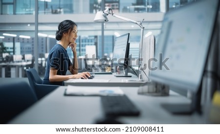 In Big Diverse Corporate Office: Portrait of Beautiful Asian Manager Using Desktop Computer, Businesswoman Managing Company Operations, Analysing Statistics, Commerce Data, Marketing Plans. Royalty-Free Stock Photo #2109008411