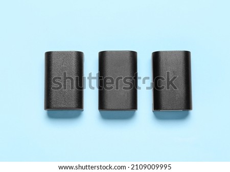 Three batteries for camera on blue background, top view
