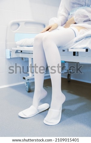 Anti-embolic surgery compression hosiery. Operating room in a hospital. Surgical equipment with operating table. Medical device for emergency patient in blue tone style. Clinic interior background. Royalty-Free Stock Photo #2109015401