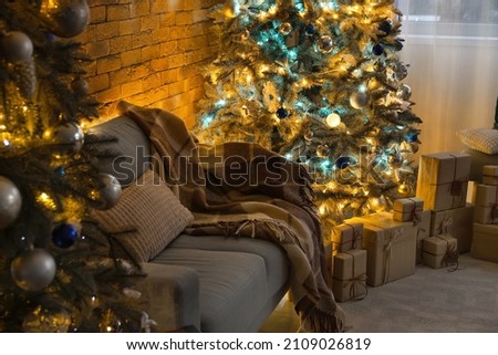 Interior of dark living room with Christmas trees and sofa