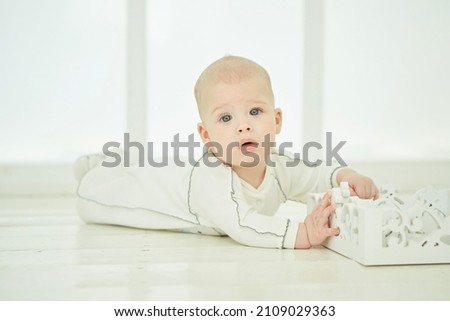 Little newborn baby boy lying in white clothes on white blanket background.