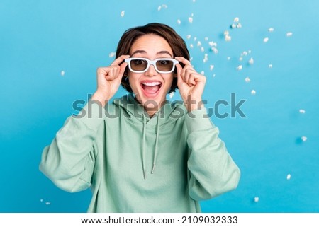 Photo of sweet excited woman wear green sweatshirt arms sunglass flying popcorn isolated blue color background