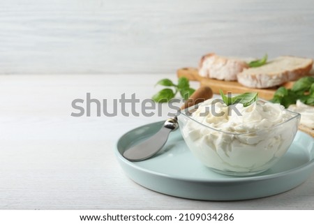 Tasty cream cheese with basil on white wooden table. Space for text Royalty-Free Stock Photo #2109034286