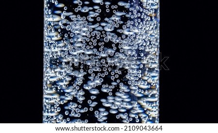 A glass of sparkling clean water on a black background. Aspirin dissolves in water. Small air bubbles in the water and on the walls of the glass. The medicine. Water for people on earth.