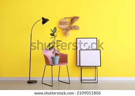 Blank poster with stylish chair near color wall