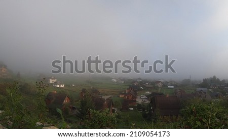 Morning fog dissipates in the mountains Carpathians. Morning fog moves and rises up summer morning in a mountain valley. Nature landscape, natural scenery, rural background, city in fog.