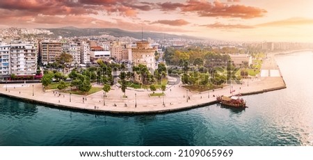 Aerial panoramic view of the main symbol of Thessaloniki city - the White Tower with boat tour ship at the pier. Concept of travel landmarks in Greece and urban development. Royalty-Free Stock Photo #2109065969