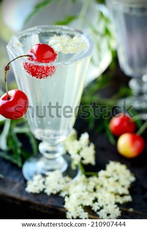 Summer refreshing drink from the flowers of the white pith and rind of lemon in two glass goblets on a wooden background with flowers elderberry . The concept of healthy organic food and natural