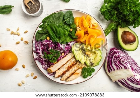 Plate with a keto diet food with chicken fillet, purple cabbage, avocado, spinach, tomatoes and nuts. Detox and healthy concept. Keto paleo lunch.