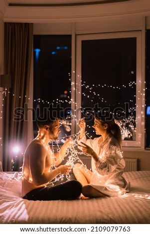 Romantic date at home in the evening in bed. couples in love sit next to each other. copy space.