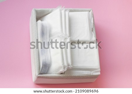 white box with feminine sanitary pads on pink background