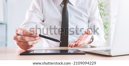 Loan officer and banker offering stylus and pad to sign document with electronic signature, panoramic image with selective focus
