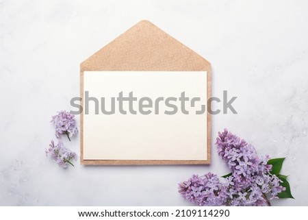 Flowers composition. Envelope, sheet of paper and lilac flowers and on stone background. Template for your invitation or greeting card. Flat lay, top view