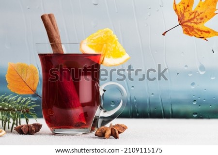 Big mug with tea, bright leaves on the background of the window. A beautiful autumn theme.