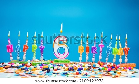 Happy birthday candle letters with number six on a beautiful blue background. Copy space Happy birthday greetings for 6 years old child, lit candles with holiday decorations