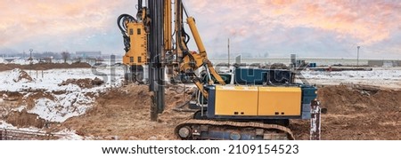 A powerful drilling rig for peeling at a construction site. Operation of the drilling rig in northern conditions. Pile foundations. Bored piles. Pagoramic view. Banner format Royalty-Free Stock Photo #2109154523