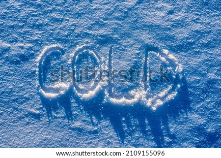The word "cold" written on the snow in sunny weather. Winter and cold weather concept.       