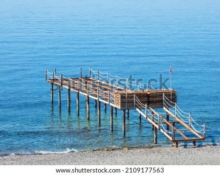 Sea pier with a wooden flooring dismantled for the winter, on a calm sunny day