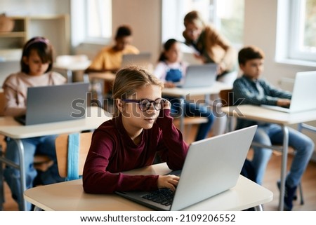 Schoolgirl using laptop during computer class at elementary school. Royalty-Free Stock Photo #2109206552