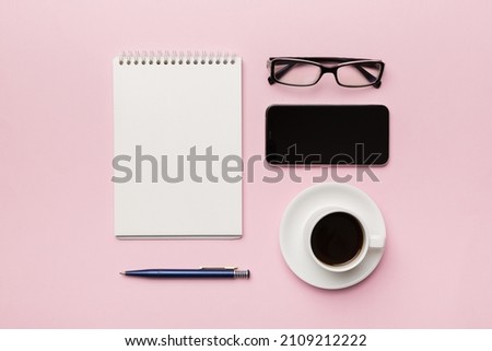 Modern office desk table with notebook, smartphone and other supplies with cup of coffee. Blank notebook page for you design. Top view, flat lay.