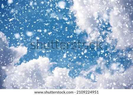Beautiful clouds on a bright blue sky, snowfall. Snow filter. Snowing. Snowflakes are falling.