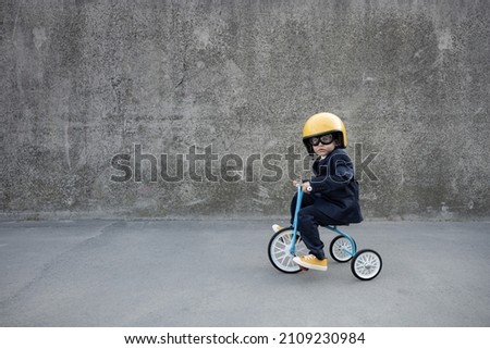 Happy child pretend to be businessman. Funny kid riding bike outdoor. Back to work, start up and business idea concept