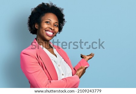 African american woman with afro hair wearing business jacket inviting to enter smiling natural with open hand  Royalty-Free Stock Photo #2109243779