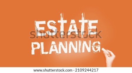 Estate planning words in pale yellow on blackboard and hand with chalk. Real estate business rent and sales concept.