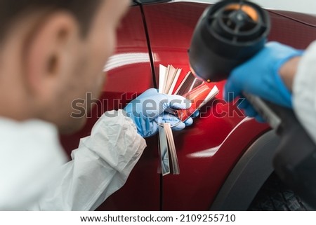 Auto painter with a 
colorist lamp and samples who selecting a shade of car paint Royalty-Free Stock Photo #2109255710