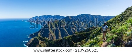 Woman hiker watching beautiful costal scenery. - Tenerife, Canary Islands, Spain. coast view, mountain Anaga Royalty-Free Stock Photo #2109260525