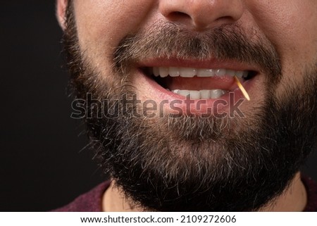 smiling male unshaven face close-up with open mouth and tongue playing with toothpick, bad man manners and violation of etiquette. Royalty-Free Stock Photo #2109272606