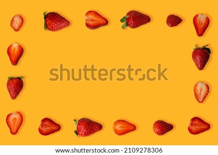 Frame made of fresh group Ripe juicy strawberries isolated on a orange background. Flat lay.