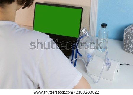 Back view close up of Sick teen girl against green screen of laptop computer while staying at home. 
Concept of conferencing, online consultation, medicine, healthcare, technology. 