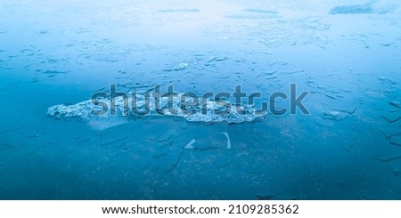 Ice pieces floating on the frozen water. Blue abstract geometry of the melting ices in the rain.