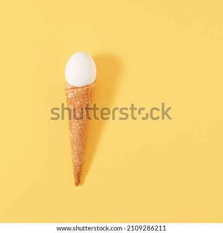 Creative Easter concept with egg and cornet on pastel yellow background. A minimal idea for the Easter holidays.