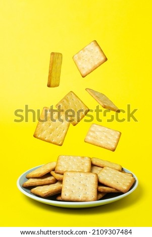 Crackers on a yellow background. Crackers fall into the plate. fresh biscuits