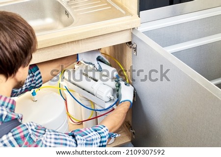 Plumber hand in gloves replace water filter cartridges at kitchen. Fix purification osmosis system. Technician installing or repairing system of water filtration. Royalty-Free Stock Photo #2109307592